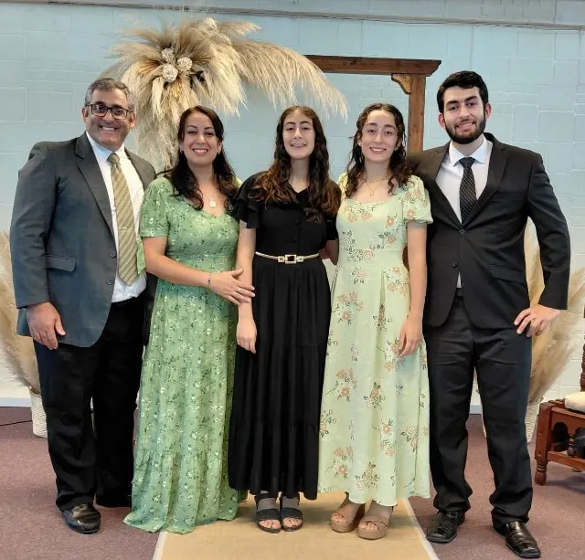 El pastor Gustavo Gonzáles, su esposa Irene y sus hijos, de pie en el salón de la iglesia.