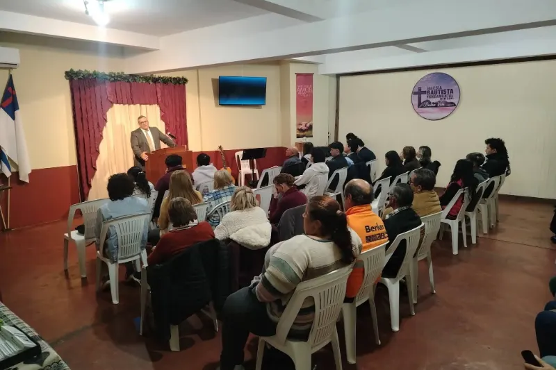 El pastor predica desde el púlpito ante la congregación sentada, en el salón de la iglesia.