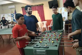 Jóvenes jugando al futbolito en el salón.