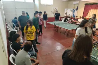 Jóvenes conversando y jugando al ping-pong durante la hora de juegos.