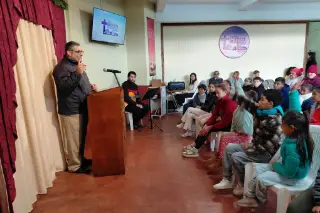 El pastor enseña a los niños, que levantan la mano para participar.