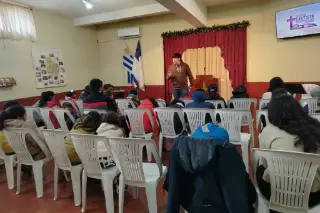 Un joven enseña a los niños sentados en el salón.